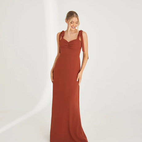 Woman wearing a rust-colored chiffon bridesmaid dress on a white background