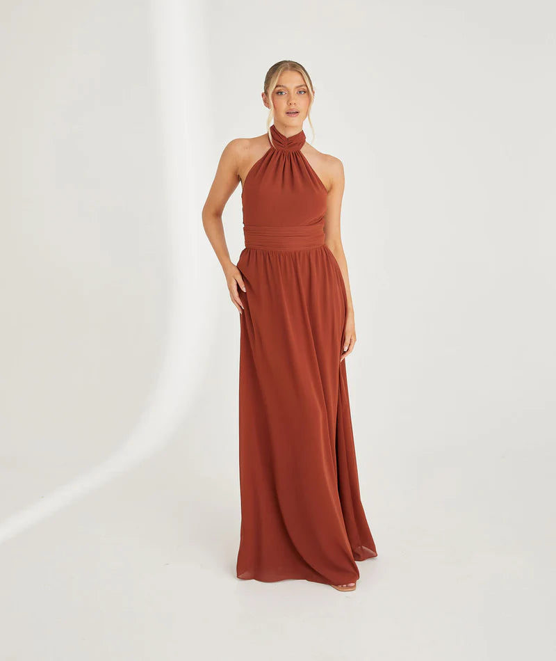 Woman wearing a rust-colored halter neck chiffon bridesmaid dress on a white background