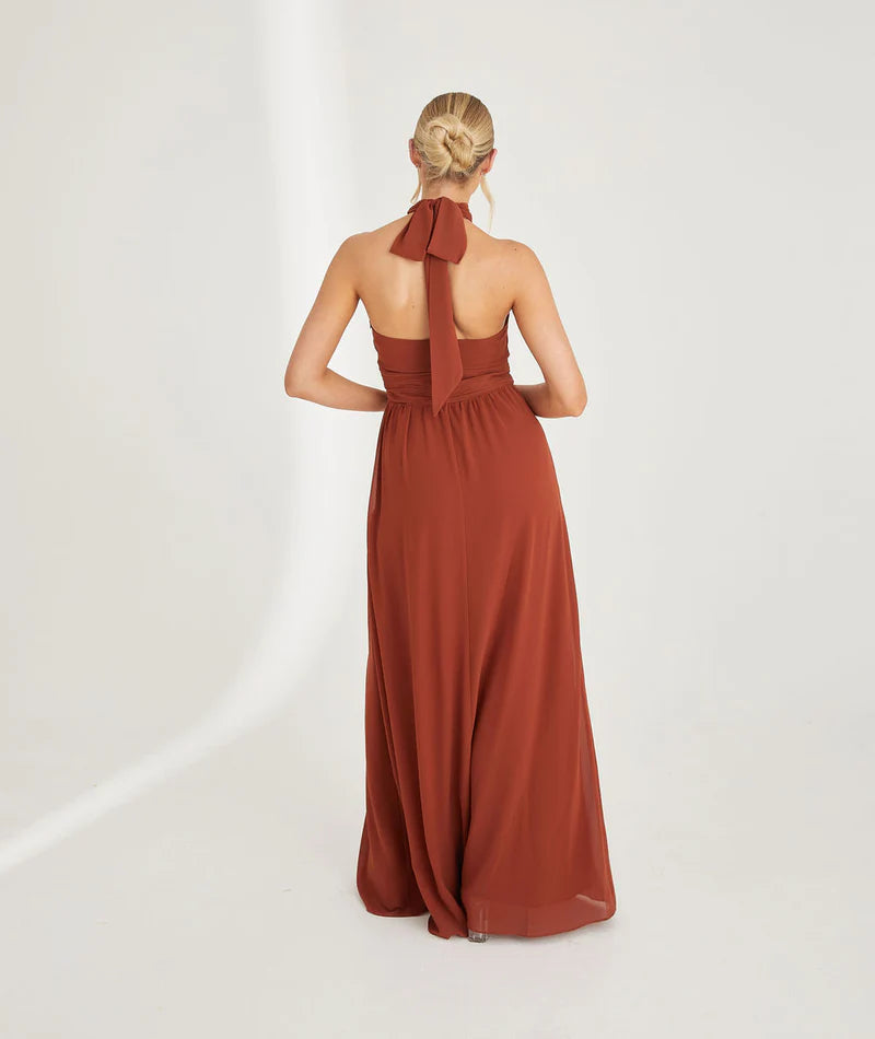 Woman wearing a rust-colored halter neck chiffon bridesmaid dress on a white background
