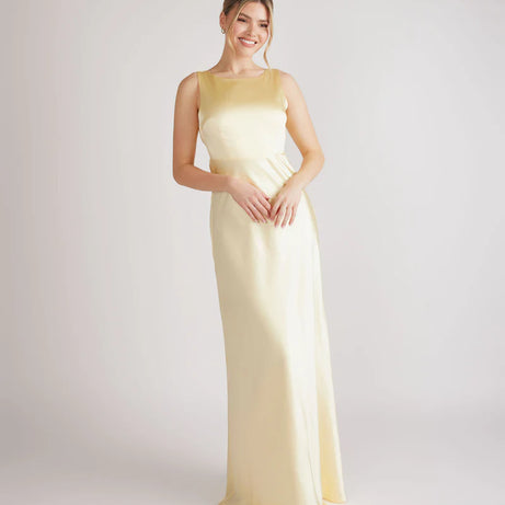 woman wearing lemon satin bridesmaid dress with cowl back against white background