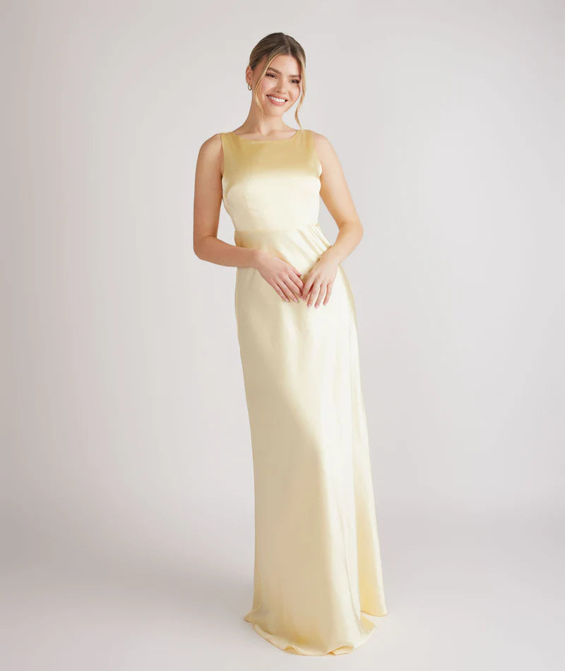 woman wearing lemon satin bridesmaid dress with cowl back against white background
