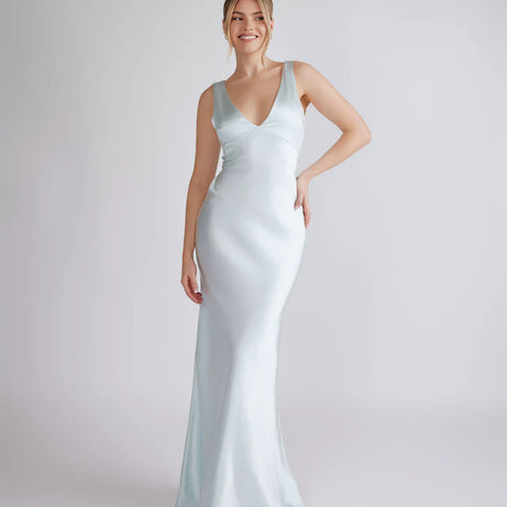 Woman wearing a light blue satin gown on a plain background