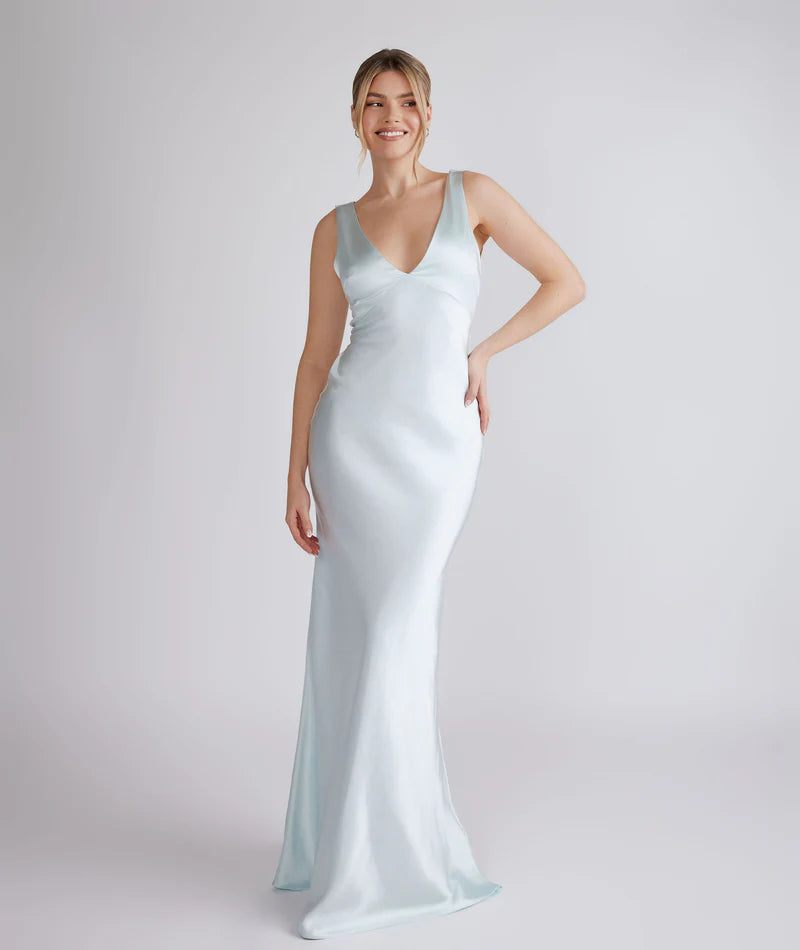 Woman wearing a light blue satin gown on a plain background