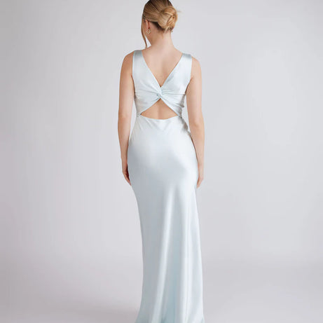 Woman wearing a light blue evening gown with a open back design on a white background