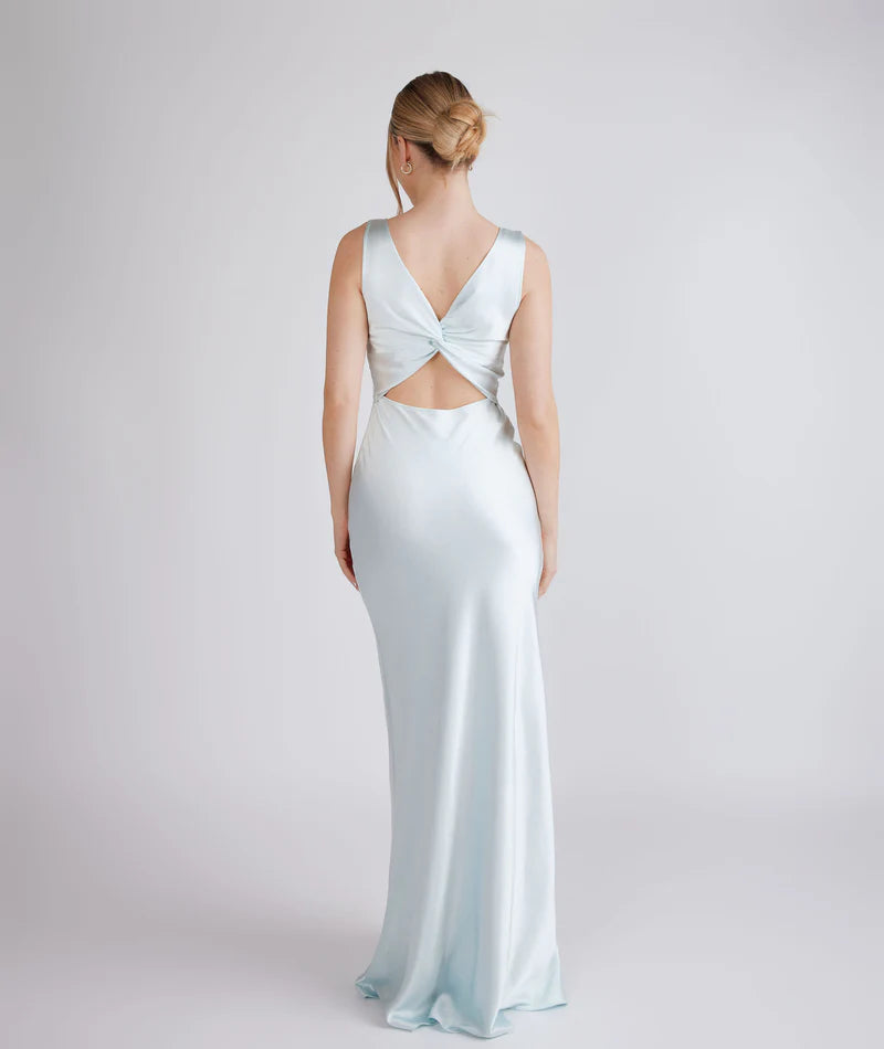 Woman wearing a light blue evening gown with a open back design on a white background