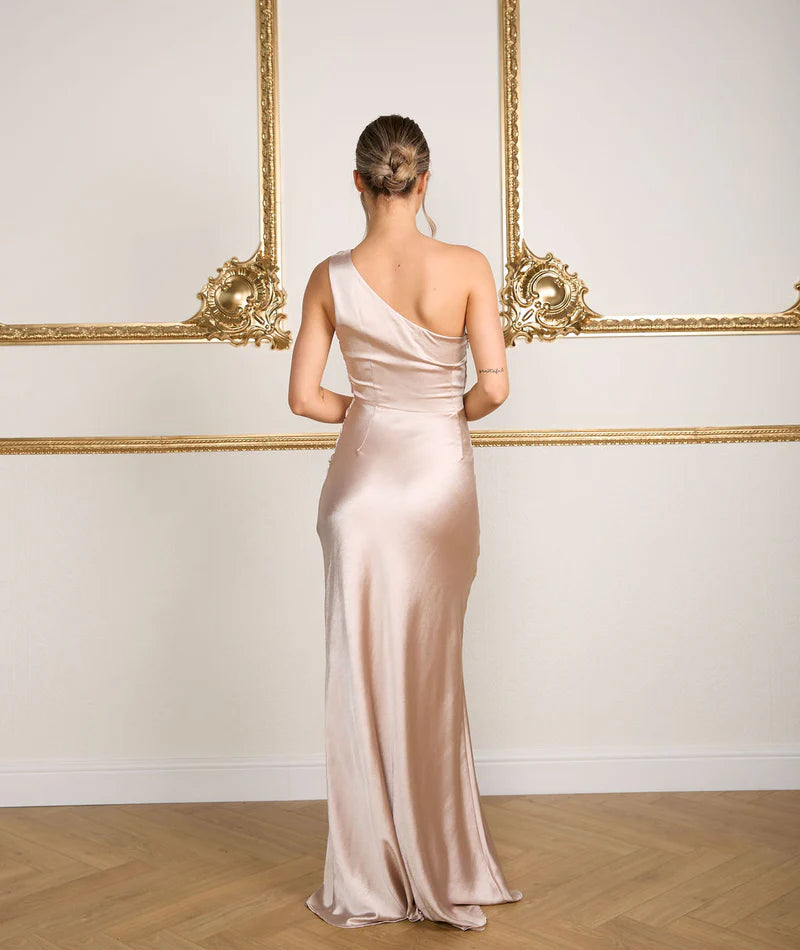 Woman in a one-shoulder bridesmaid dress standing in front of ornate wall decorations.