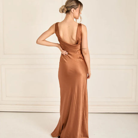Woman wearing a long teracotta satin dress with a plain background