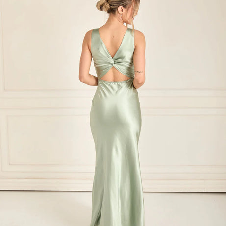 Woman wearing a light green bridesmaid gown with a backless design on a white background