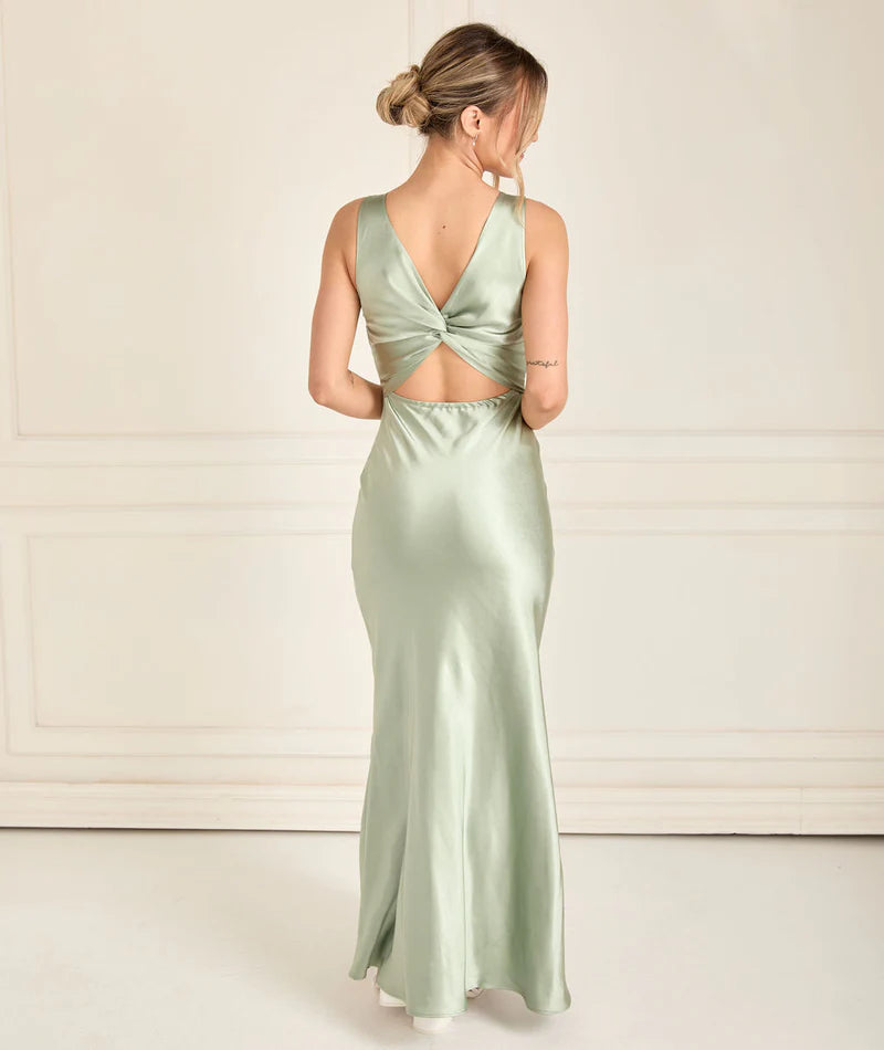Woman wearing a light green bridesmaid gown with a backless design on a white background