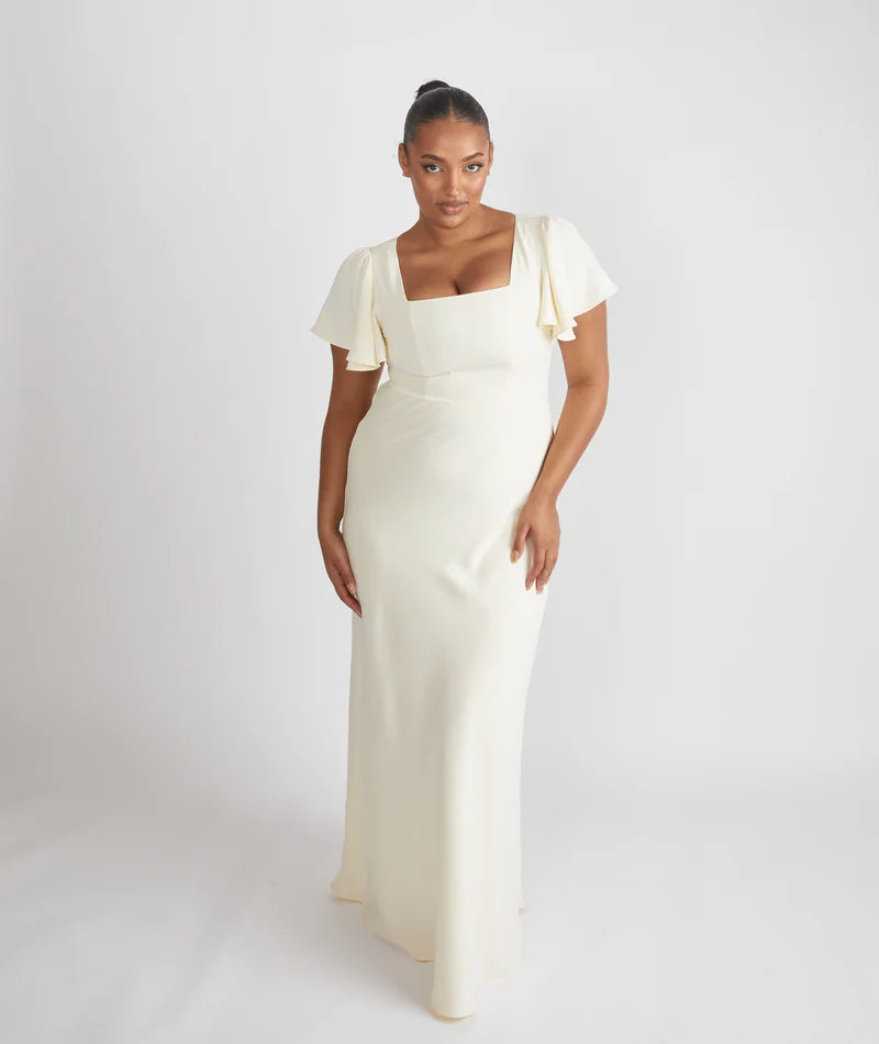 Woman wearing the Cressida, square neck flutter sleeve bridesmaid dress by Six Stories in colour almond