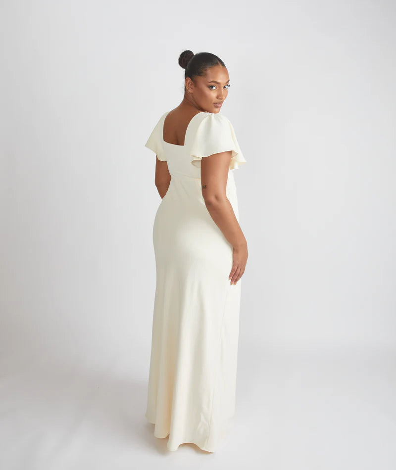 Woman wearing the Cressida, square neck flutter sleeve bridesmaid dress by Six Stories in colour almond