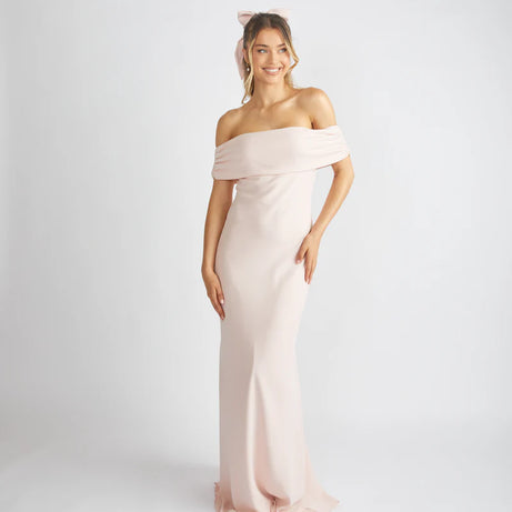 Woman wearing a light pink off-shoulder gown on a white background