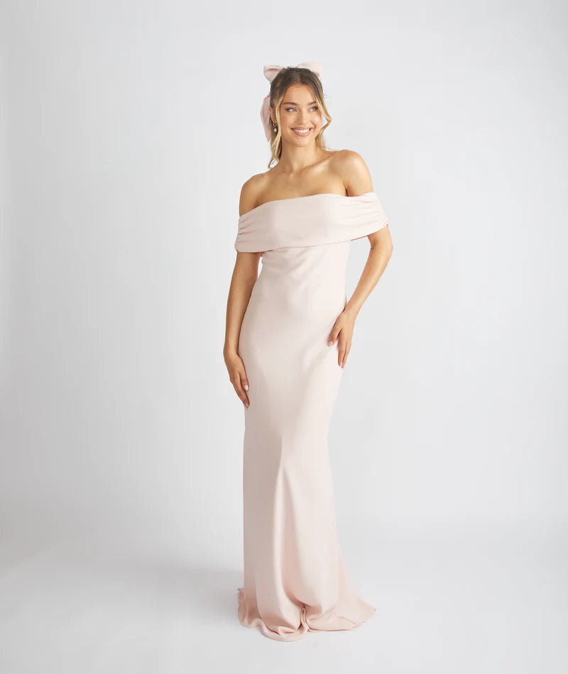 Woman wearing a light pink off-shoulder gown on a white background
