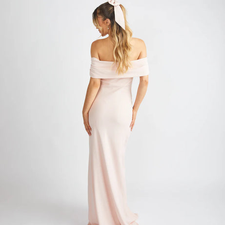 Woman wearing a light pink off-shoulder gown against a white background