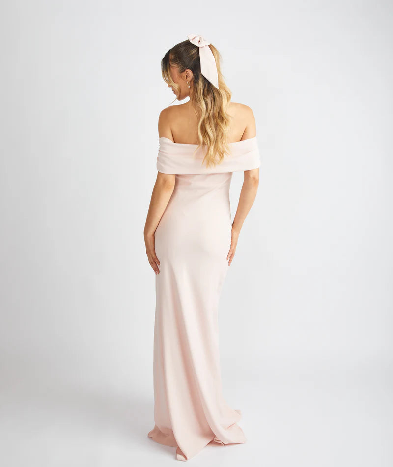 Woman wearing a light pink off-shoulder gown against a white background