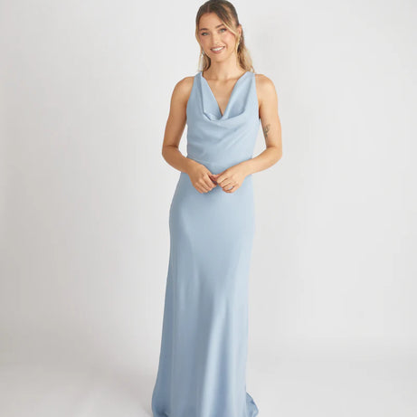 woman wearing dusty blue cowl front bridesmaid dress against a white background