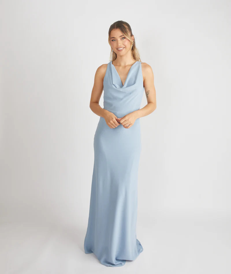 woman wearing dusty blue cowl front bridesmaid dress against a white background