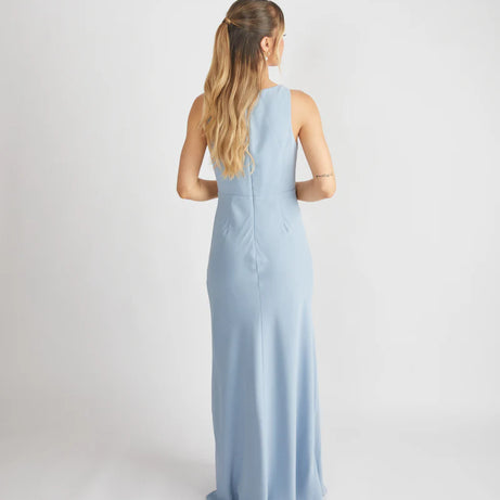 woman wearing dusty blue bridesmaid dress against a white background
