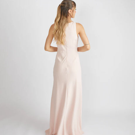 woman wearing a light pink crepe bridesmaid dress against a white background