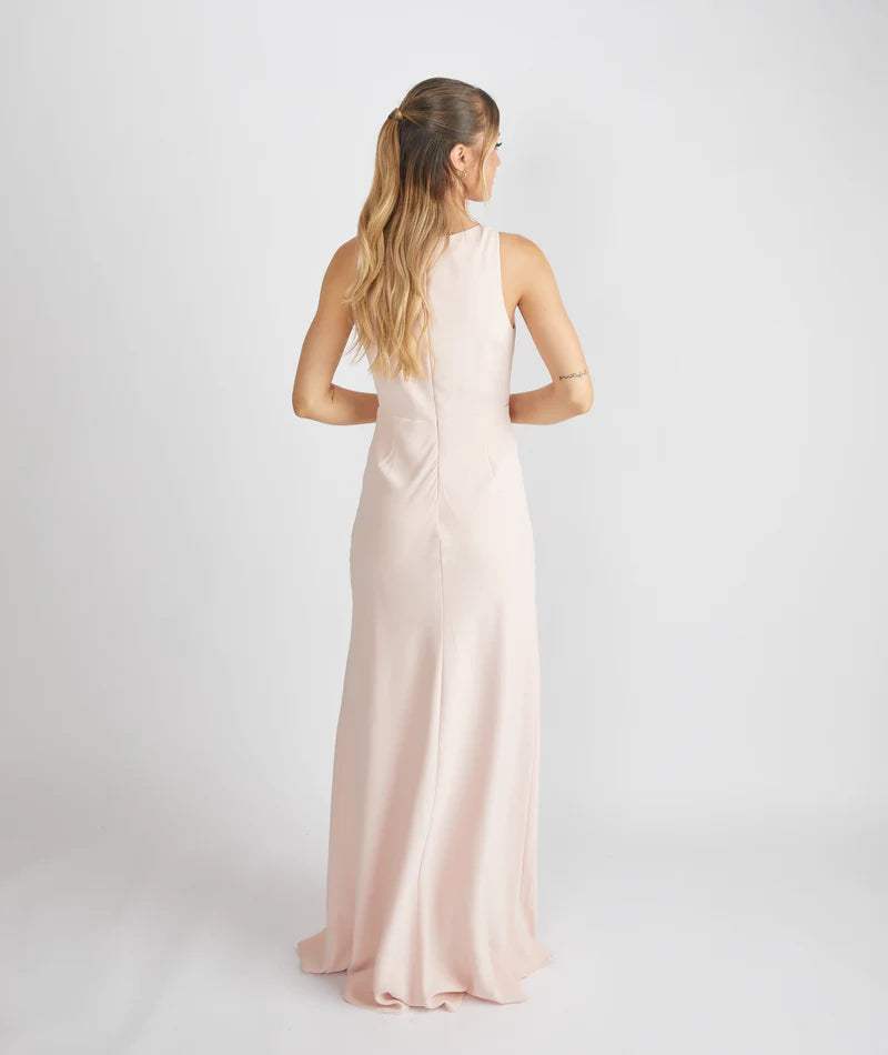 woman wearing a light pink crepe bridesmaid dress against a white background