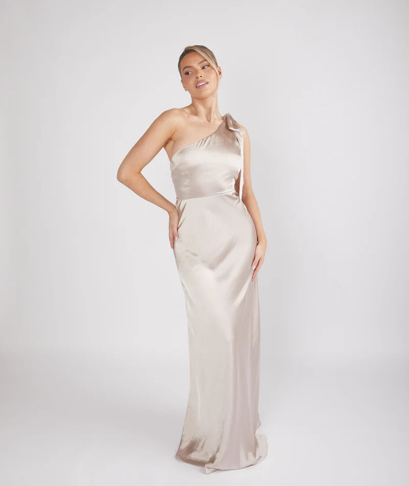 Woman wearing a one-shoulder beige evening gown on a white background
