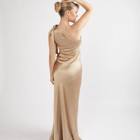 Woman wearing a champagne satin one-shoulder bridesmaid dress on a white background