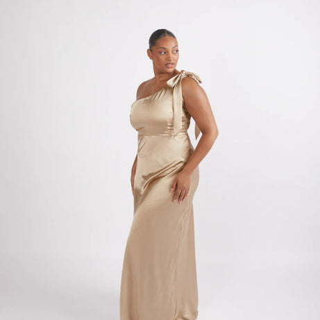 Woman wearing a champagne satin one-shoulder bridesmaid dress on a white background