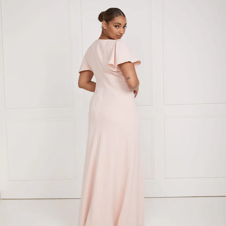 Woman wearing a long, light pink dress against a white background