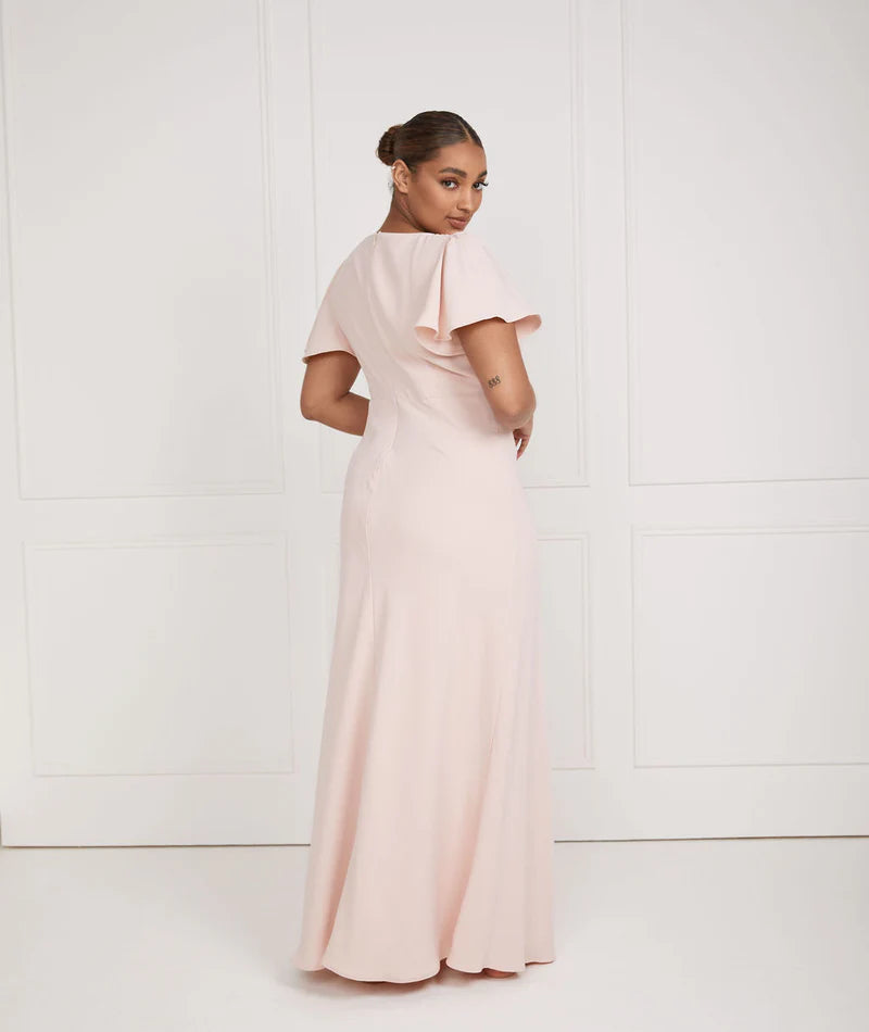 Woman wearing a long, light pink dress against a white background