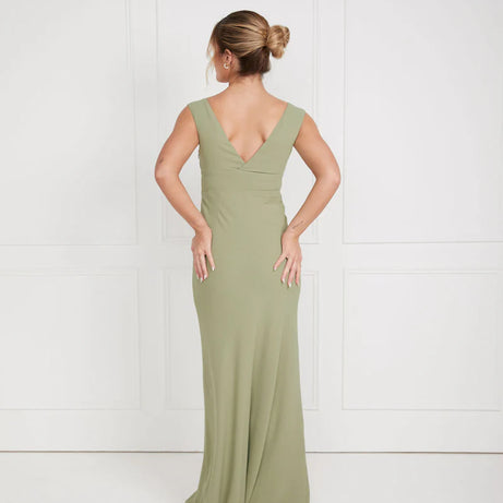Woman wearing a sage green v neck bridesmaid dress against a white background