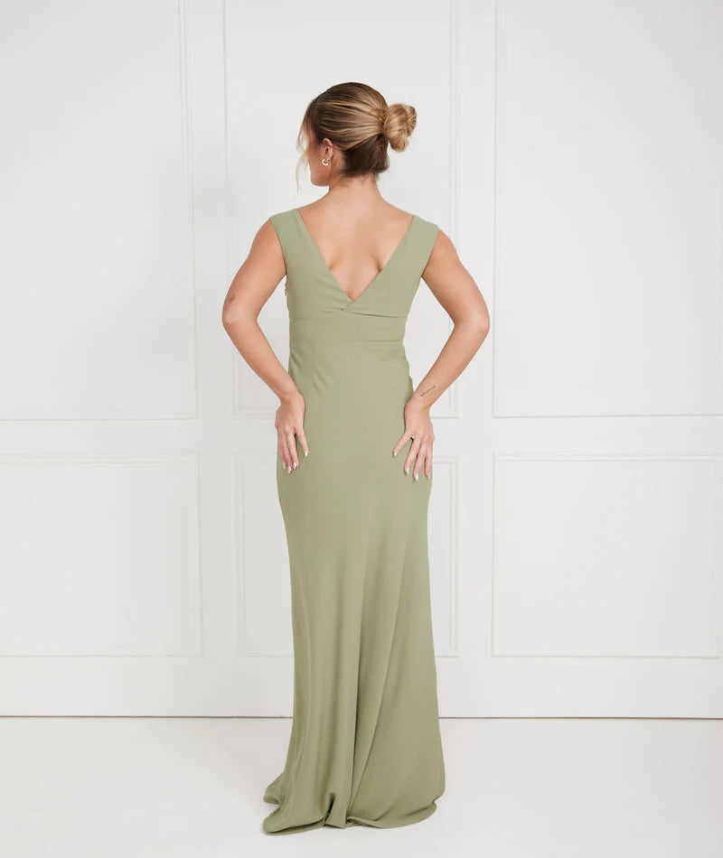 Woman wearing a sage green v neck bridesmaid dress against a white background