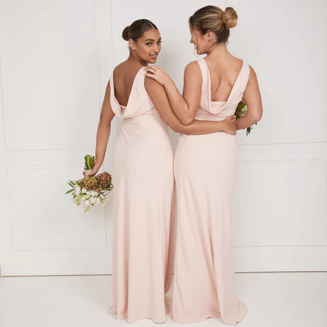 Two girls wearing soft pink bridesmaid dresses with cowl back by six stories