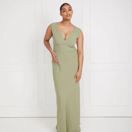 Woman wearing a sage green v neck bridesmaid dress against a white background