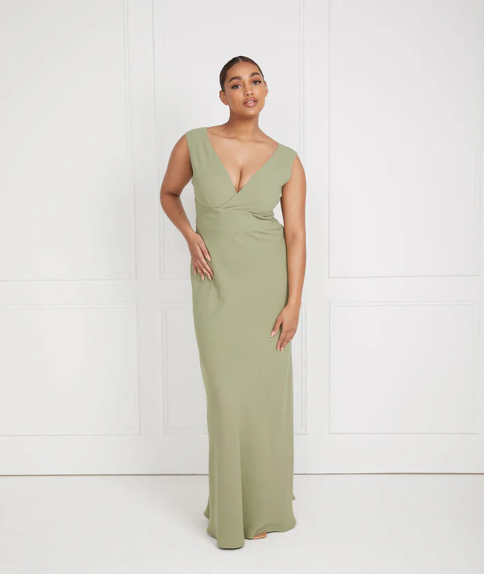 Woman wearing a sage green v neck bridesmaid dress against a white background