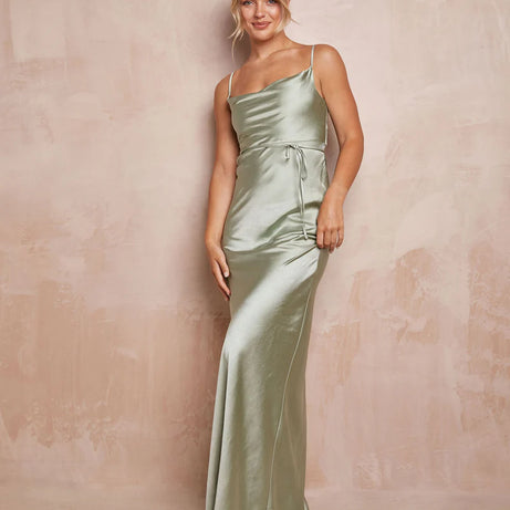 Woman wearing a long green satin dress against a beige background