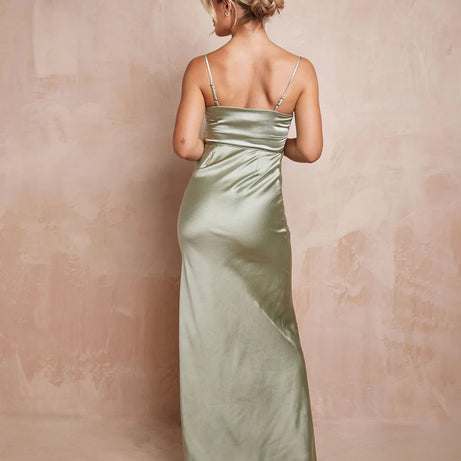 Woman wearing a long, light green satin dress against a beige background