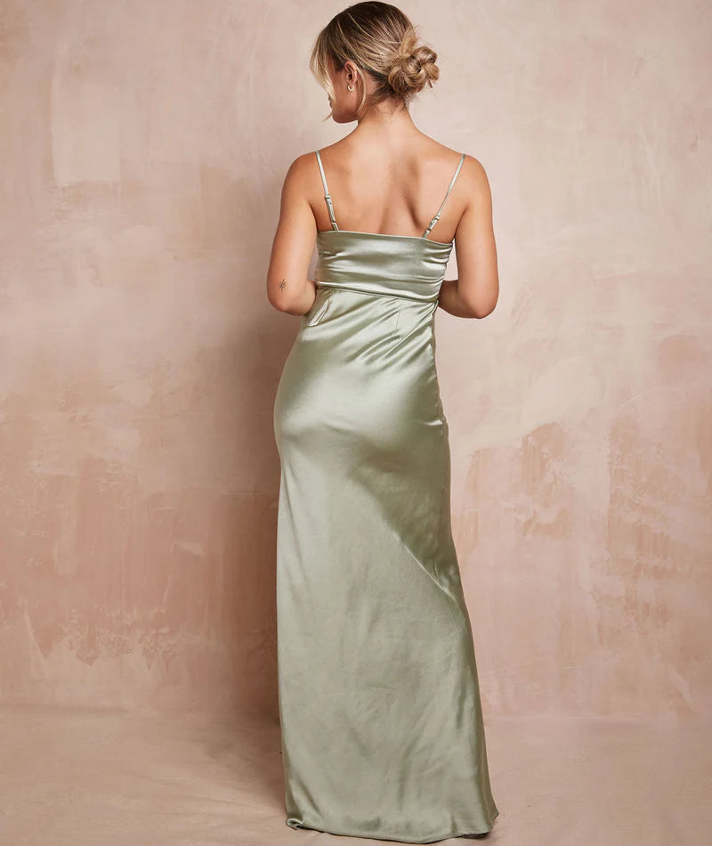 Woman wearing a long, light green satin dress against a beige background