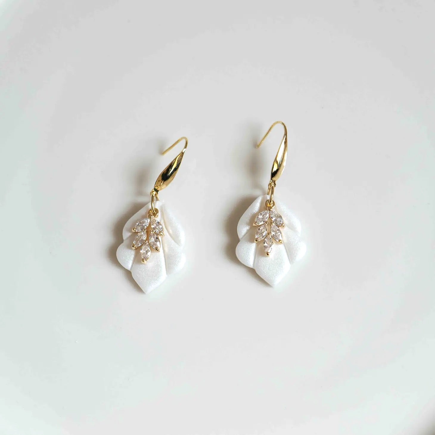 Bring a modern yet timeless touch to your bridal ensemble with the Sophie Ivory and Gold Bridal Earrings. Delicately crafted for the bride who loves effortless elegance, these earrings combine sleek design with soft, romantic details, offering a unique accessory that feels both elevated and easy to wear. Whether you're walking down the aisle, attending a rehearsal dinner, or dressing for a special occasion, the Sophie earrings are the perfect finishing touch