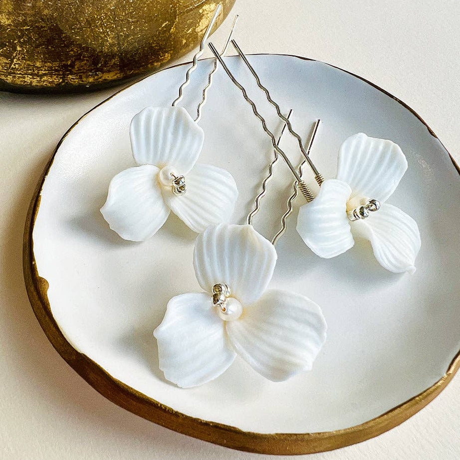 Elevate your bridal hairstyle with timeless sophistication and romantic charm with the Kylee Ivory Floral Hair Pins. Sold as a set of three, each pin is a delicate work of art, meticulously handcrafted to add a soft, feminine touch to your special day. Whether you're walking down the aisle, attending an engagement party, or preparing for a bridal photoshoot, these floral hair pins are the perfect accessory to complete your look.