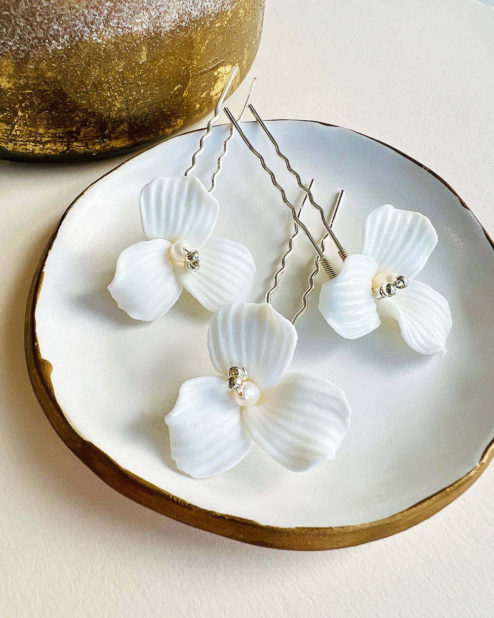 Elevate your bridal hairstyle with timeless sophistication and romantic charm with the Kylee Ivory Floral Hair Pins. Sold as a set of three, each pin is a delicate work of art, meticulously handcrafted to add a soft, feminine touch to your special day. Whether you're walking down the aisle, attending an engagement party, or preparing for a bridal photoshoot, these floral hair pins are the perfect accessory to complete your look.