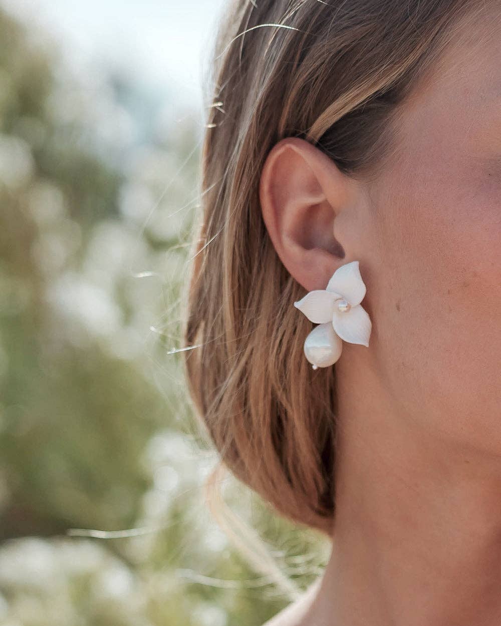 Make a statement of timeless sophistication on your wedding day with the Laurel Pearl Drop Earrings — a striking blend of modern design and classic beauty. Thoughtfully handcrafted, these earrings feature delicate ivory clay flowers paired with a luminous pear-shaped pearl that adds effortless refinement to any bridal or special occasion look.