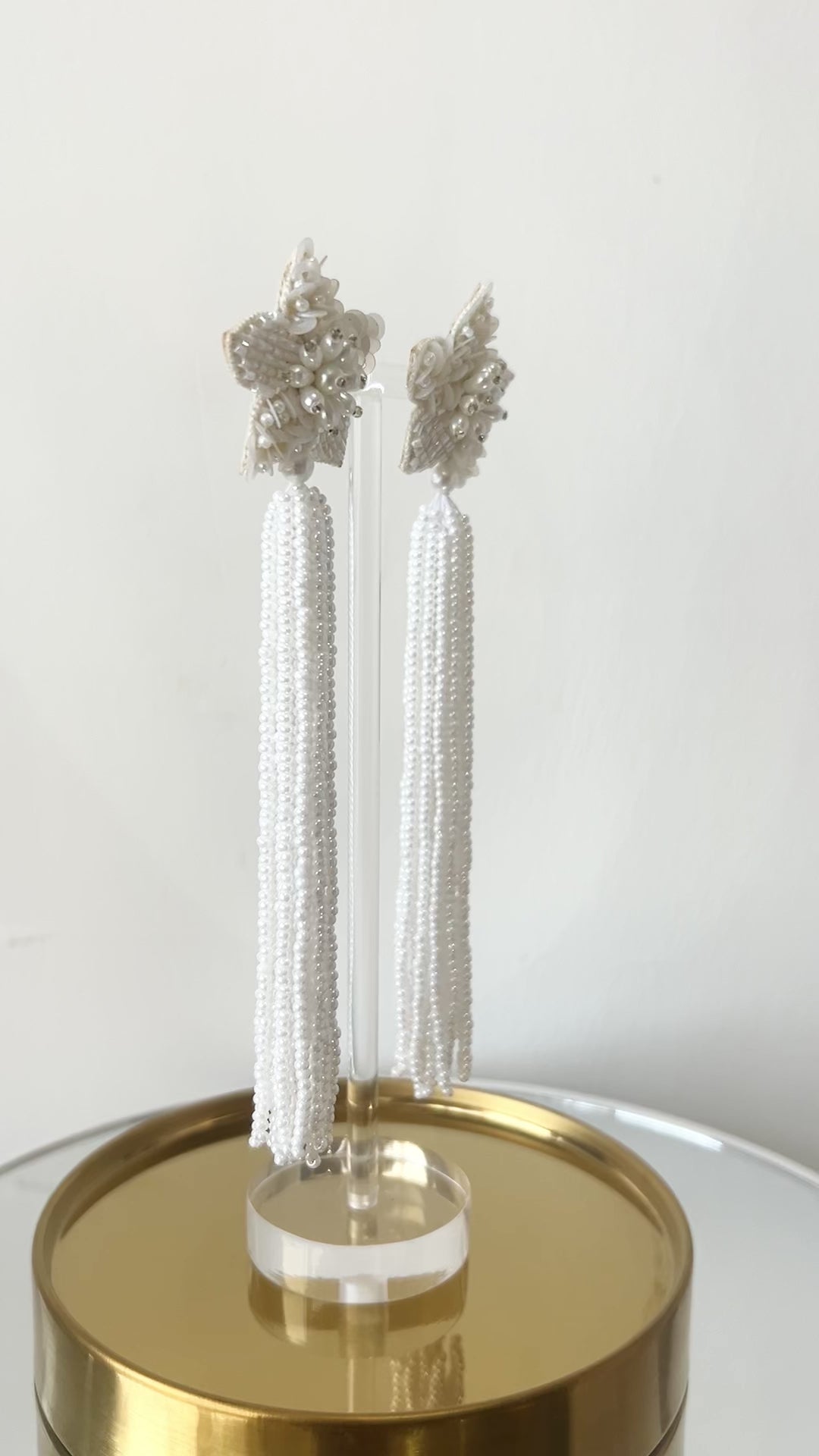 Video of long star shaped ivory beaded tassel earrings against a white backdrop.