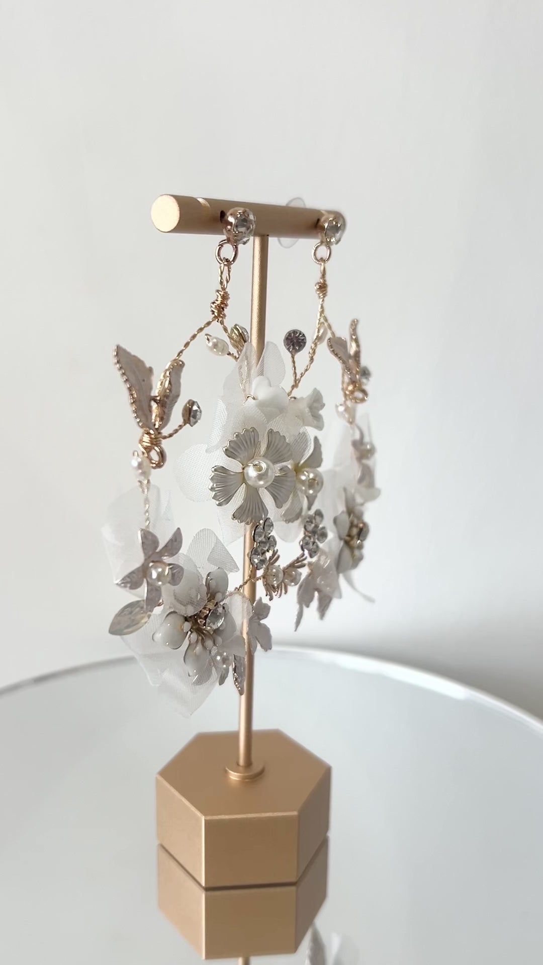 Pair of floral earrings on a gold stand against a light background