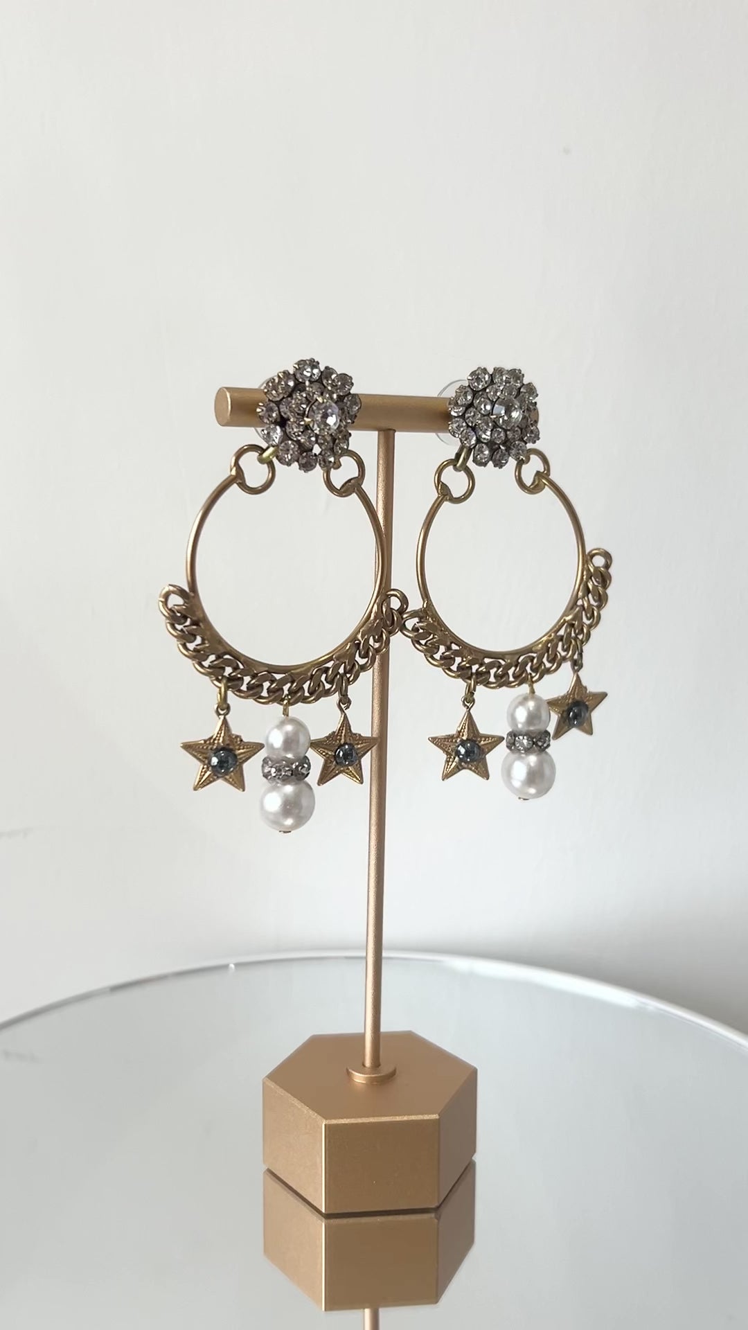 A pair of earrings featuring a gold-colored antique chain circlet with a Swarovski crystal cluster at the top, adorned with pearl, crystal, and starlet charms.